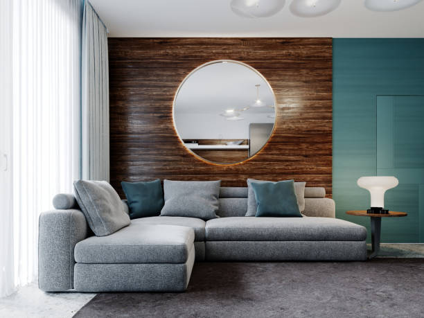 istock Corner gray sofa against a wooden wall with horizontal stripes and a round mirror with a night table with a lamp in the living room. 1263895839