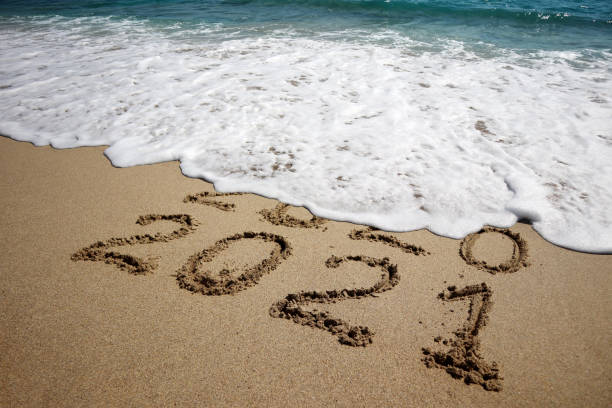 New year 2021 New year 2021 and old year 2020 written on sandy beach with waves calendar date photos stock pictures, royalty-free photos & images