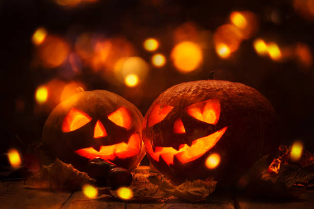 istock Halloween pumpkin head jack o lantern with burning fire background, wooden table with light bokeh garland. Beautiful Holiday Autumn Composition 1263899316
