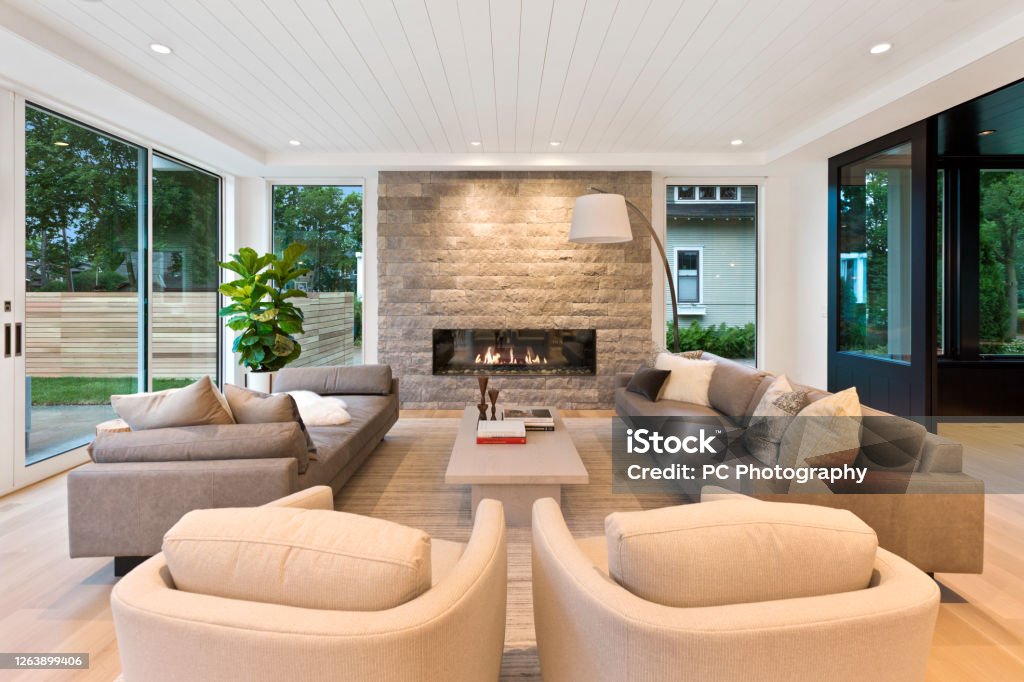 Mid century modern style in family room surrounded by windows New home in Minnesota with wide linear fireplace Home Interior Stock Photo