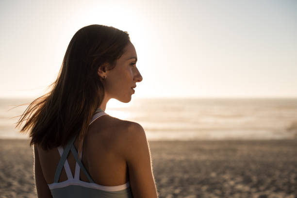 istock Woman enjoying beautiful sunset on the beach 1263901796