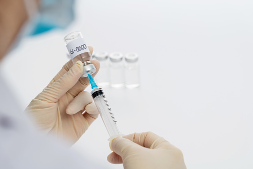 Doctor's hand holding syringe and Covid-19 vaccine vial.