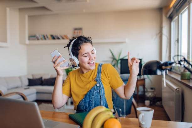 jeune femme excitée dansant et écoutant la musique après le travail - suing photos et images de collection