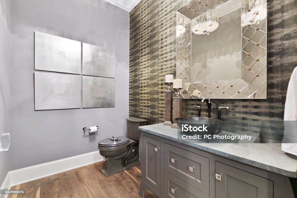 Interesting wallpaper and decor in new bathroom Vessel sink with two handle faucet and wood floors Bathroom Stock Photo