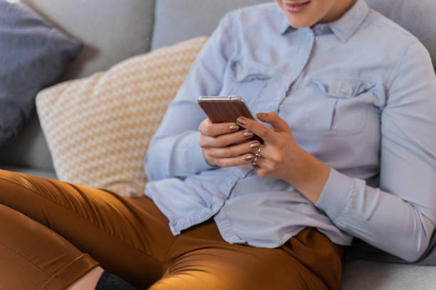 istock Woman sitting on sofa and using smartphone 1263905712