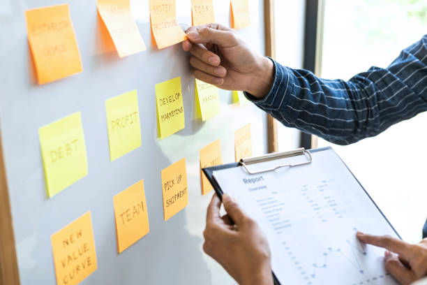 istock Two creative Business people meeting and planning use post it notes on board to share idea, Analysis data charts and graph with teamwork strategy brainstorming 1263905851