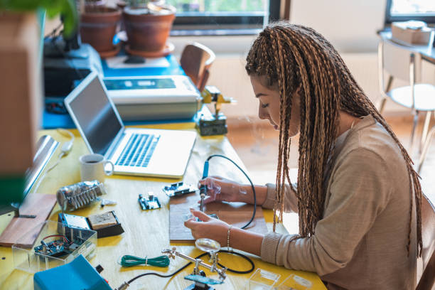istock Woman electronics engineer is soldering circuit  board in her workshop stock photo 1263907373