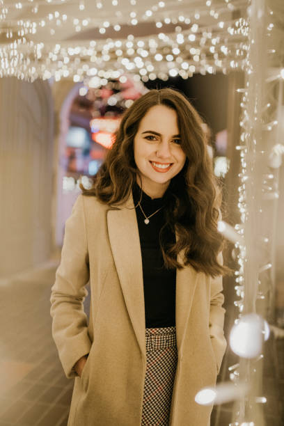 istock Young woman standing amidst Christmas lights 1263907389
