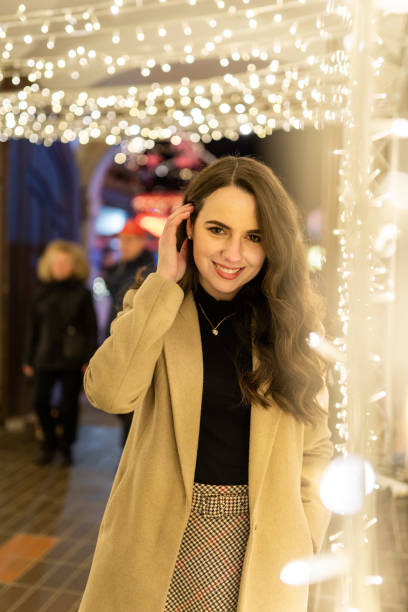 istock Young woman standing amidst Christmas lights 1263907423