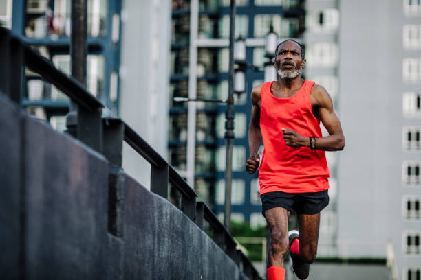 homme afro-américain aîné exécutant dans une ville - marathon photos et images de collection