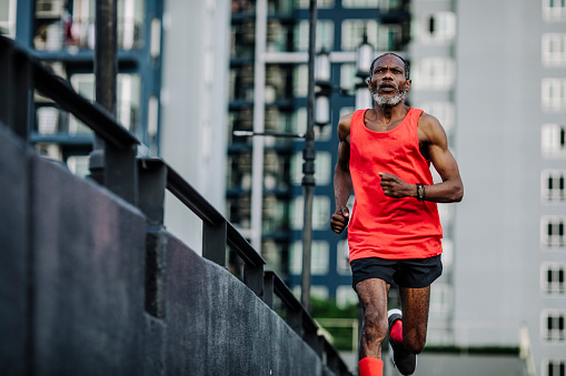 Staying healthy and active: a mature man jogging alone in an urban area.