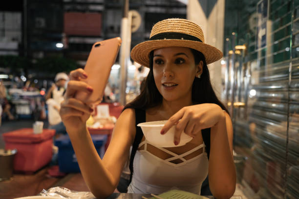 istock Young Mexican woman using phone in street cafe 1263909329