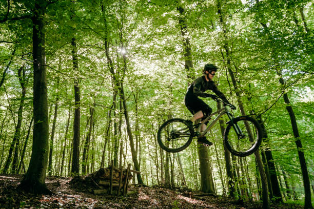 istock Man on mountain bike jumping over obstacles in forest 1263910841