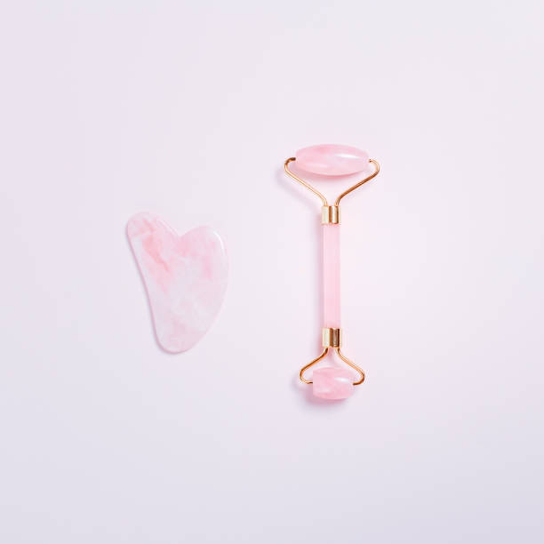 istock Beauty roller, gua sha on pastel pink top, square format. Tools for skin care routines, top view 1263910855