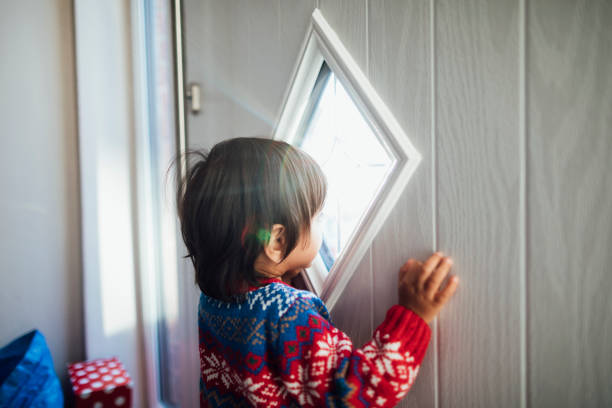 Peeking Through the Window A boy standing with his hands resting on a front door at home, looking through a window in the door. looking out front door stock pictures, royalty-free photos & images