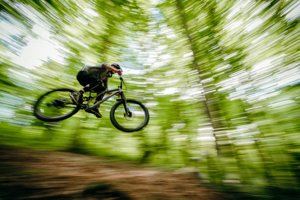 istock Man on mountain bike jumping over obstacles in forest 1263911577