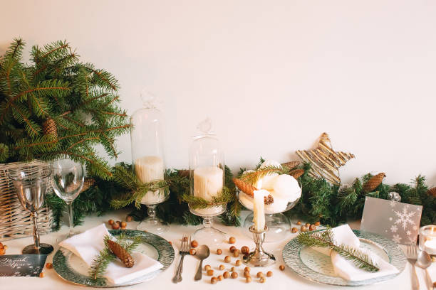 Festive table setting for Christmas and New Years with green spruce branches, candles and cutlery. Soft focus.