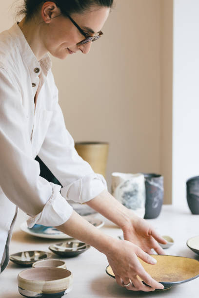 istock Woman Working at Gallery Arangin Pottery Pieces on a Table 1263912569