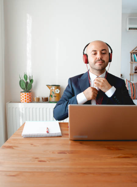 business man correcting his tie for video conferencing in his home office. stock photo