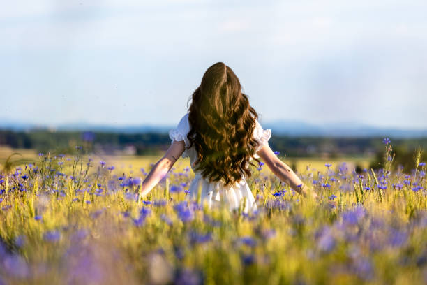 Woman standing amidst wildflowers on agricultural field