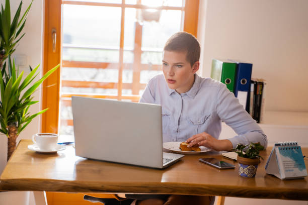 istock Woman eating croissant using laptop 1263916879