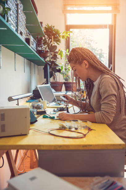 istock Woman electronics engineer is soldering circuit  board in her workshop stock photo 1263918080