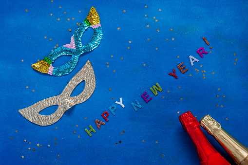Two Carnival mask and Two champagne bottles. New Year concept.  Top view, Close up on blue background.