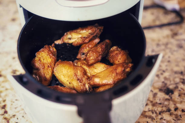 Chicken wings in a air fryer on a kitchen counter stock photo