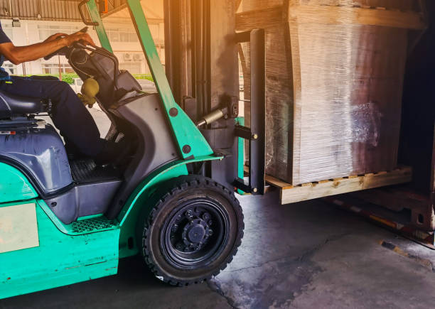 istock Worker driving forklift loading and unloading shipment carton boxes and goods on wooden pallet from container truck to warehouse cargo storage in logistics and transportation industrial 1263924390