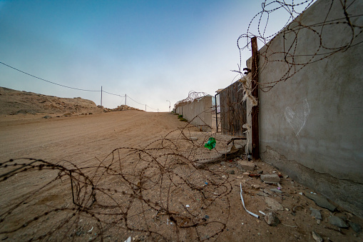 Barbed wire and wall next to road under clear sky