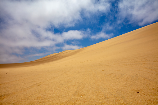 View of dunes in desert and clouds in blue sky