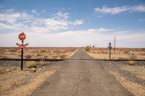 Railway crossing on empty road on desert