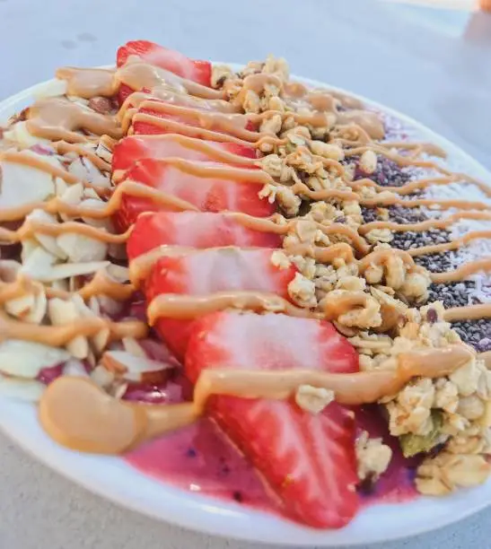 A vegan, healthy breakfast made with fresh fruit and nuts and topped with vegan peanut butter