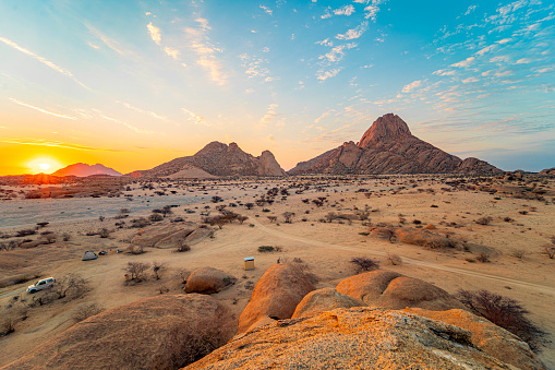 View of setting sun over desert with rock formations