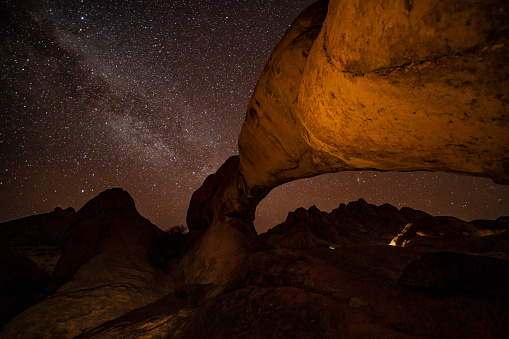 Milky Way in starry sky over arch rock formation in desert