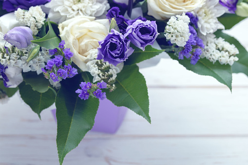 Beautiful bouquet of white and purple flowers on a white wooden background. Flower arrangement for your beloved.