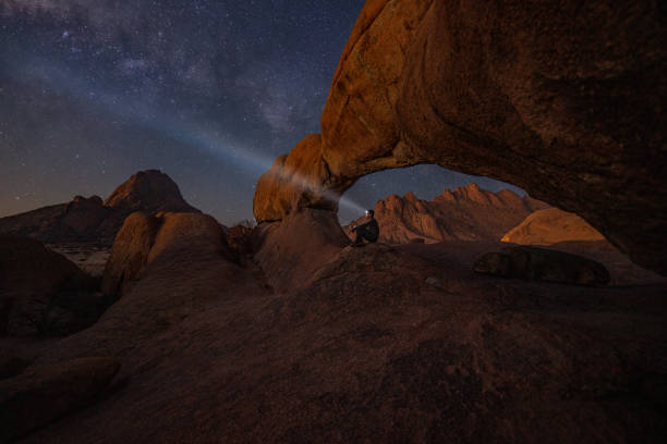 Man sitting under starry sky with a light on his head