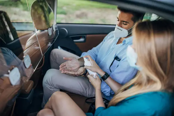 Photo of Couple with protective face masks ridding in back seat of a taxi.