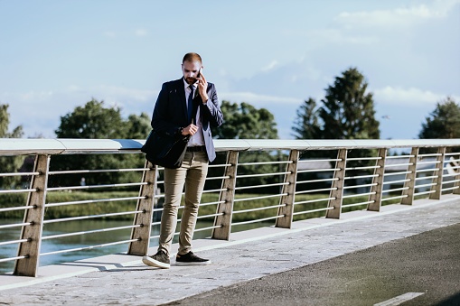 Man in suit standing on bridge talking on phone