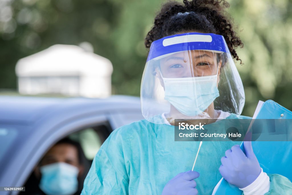 Nurse wearing PPE smiles at drive through testing site Face Shield Stock Photo