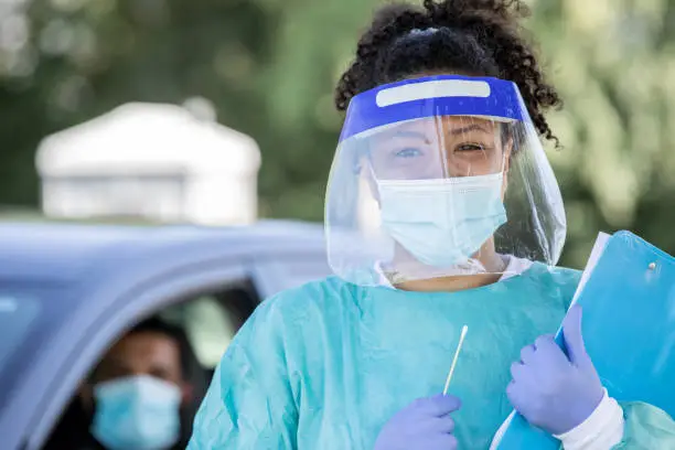 Nurse wearing PPE smiles at drive through testing site