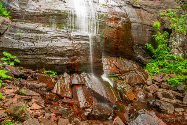 belle chute d’eau de montagne rebondissant de la roche massive rouge - waterfall rock mountain bright photos et images de collection