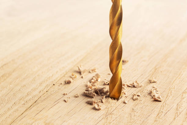 istock drill makes a hole in the wooden oak table with wood 1263936638