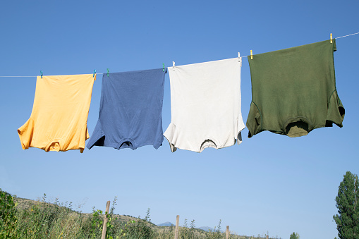 White T-shirts hangs on a rope  in a sunny summer day with clear blue sky at the background