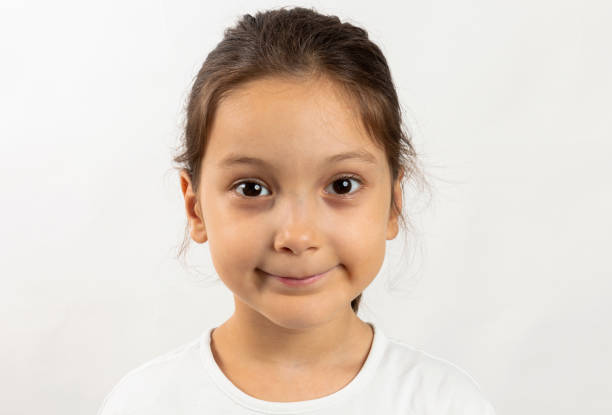 Six year old girl is looking at camera. White background.