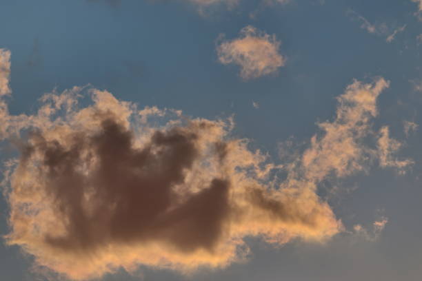 istock tuft of white cloud, backlit by sunlight, floating under a blue sky. 1263949324