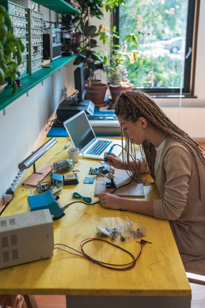 istock Woman electronics engineer is soldering circuit  board in her workshop stock photo 1263964371