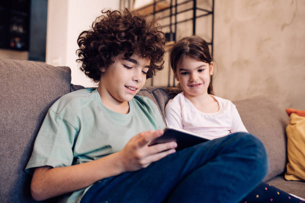 istock Brother and sister enjoying on the sofa and using tablet together 1263965538
