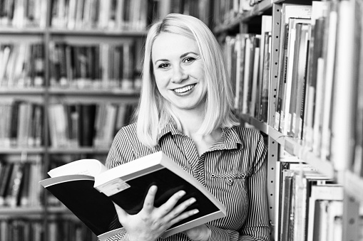 In the Library - Pretty Female Student With Books Working in a High School - University Library - Shallow Depth of Field