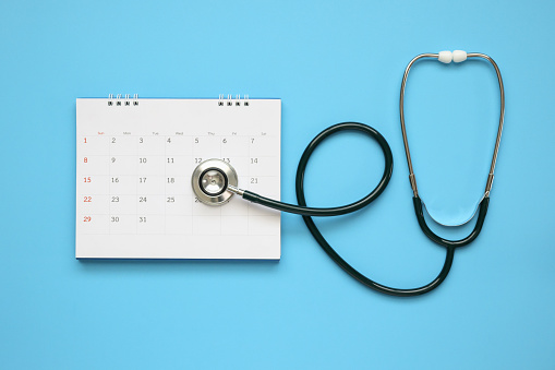 Estetoscopio con fecha de página de calendario en el concepto médico de cita médico de fondo azul photo